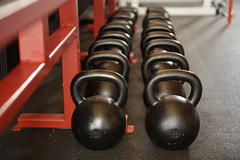 Black kettlebells lined up in a gym, ready for fitness training. HD wallpaper