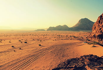 Explore the stunning beauty of Wadi Rum's arid desert landscape, bathed in warm sunset hues. HD wallpaper