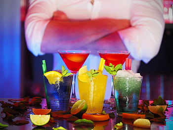 Colorful cocktails with citrus slices on a bar, perfect for nightlife settings. HD wallpaper