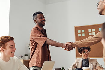 Business team members shaking hands during a meeting, demonstrating cooperation and teamwork. HD wallpaper