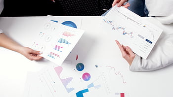 Hands holding business charts and graphs during a meeting, showcasing financial analysis and investment strategy. HD wallpaper