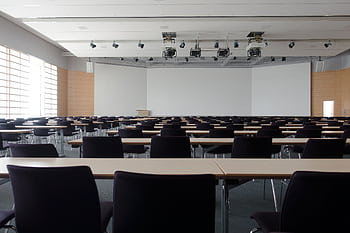 Spacious contemporary conference room with rows of tables and chairs, ready for meetings. HD wallpaper