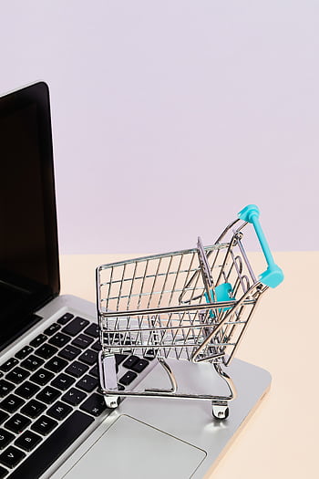Mini shopping cart on a laptop symbolizes online shopping and e-commerce themes. HD phone wallpaper