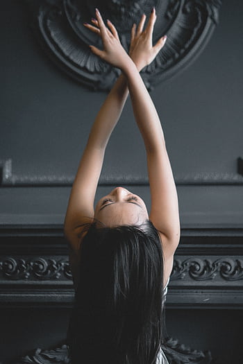 A young woman elegantly posing in a contemporary dance style against a decorative backdrop, embodying grace and flexibility. HD phone wallpaper