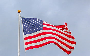 A vibrant of the American flag waving proudly against a clear blue sky, symbolizing dom. HD wallpaper