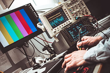 Technician operating laboratory electronic testing and measurement devices with colorful display. HD wallpaper