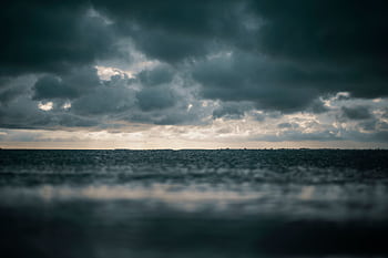 A captivating view of the ocean with dramatic dark clouds above, presenting a moody and dramatic seascape. HD wallpaper