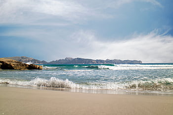 Capture of a serene beach in Illes Balears, Spain with gentle waves and a clear sky. HD wallpaper