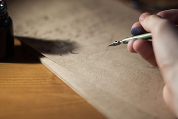Close-up of a hand writing with a fountain pen on vintage paper, capturing the art of calligraphy. HD wallpaper