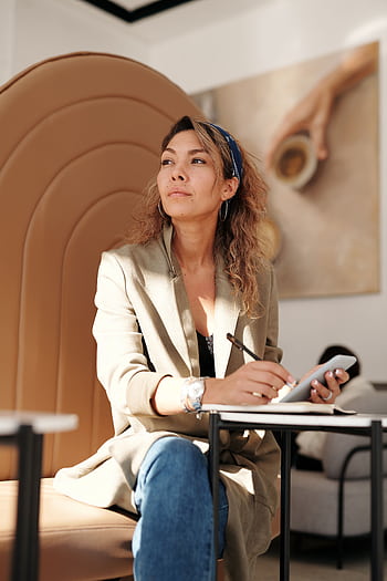 Confident woman in blazer taking notes with pen and smart in cafe. HD phone wallpaper