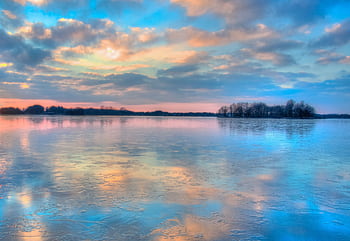 A breathtaking view of a sunset reflecting on an icy lake with colorful clouds. HD wallpaper