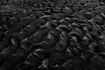Close-up of textured black sand dunes in monochrome, showcasing natural patterns and textures. HD wallpaper