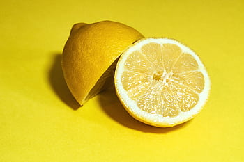 Close-up of a juicy lemon sliced in half, set against a vivid yellow background. HD wallpaper