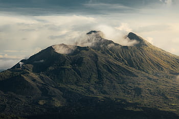 A breathtaking aerial view of the majestic Mount Batur in Bali, shrouded in mist and clouds. HD wallpaper