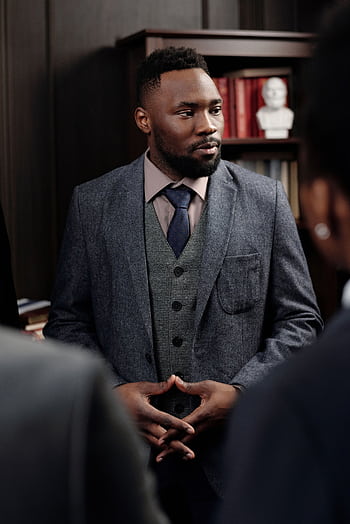 Confident businessman in a suit leading a discussion in a formal office setting. HD phone wallpaper