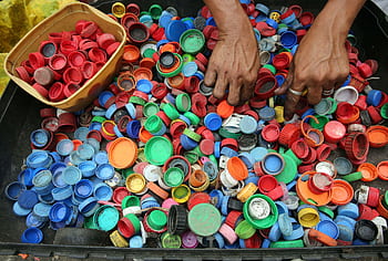 A vibrant assortment of plastic bottle caps being sorted by hand for recycling in Manila. HD wallpaper