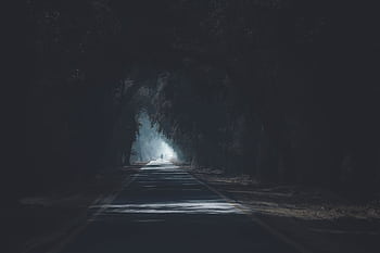 A scenic and atmospheric road with tree silhouettes creating a dark and mysterious tunnel effect. HD wallpaper