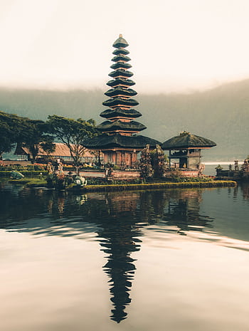 A serene view of Ulun Danu Beratan Temple with reflections on the water at sunrise, Bali. HD phone wallpaper