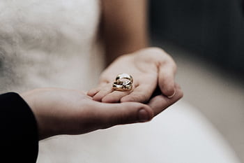 Bride holding wedding bands in a tender moment, symbolizing love and commitment. HD wallpaper