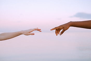 Two diverse hands reaching out across a pastel horizon, symbolizing unity and connection. HD wallpaper