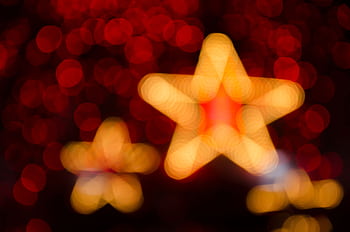 Blurred gold and red star-shaped lights creating a festive holiday atmosphere. HD wallpaper