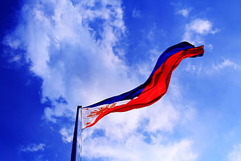 Philippine flag waving against a bright blue sky, symbolizing patriotism and dom. HD wallpaper