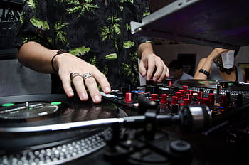 Close-up of a DJ mixing music at a club with vibrant atmosphere and crowd. HD wallpaper