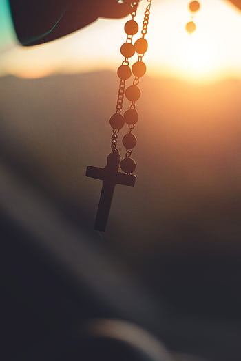 Silhouette of a rosary cross hanging with sunrise background in Brazil, capturing spiritual serenity. HD phone wallpaper
