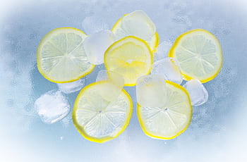 Fresh lemon slices and ice cubes on a cool surface, perfect for refreshment. HD wallpaper