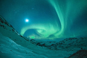 Dazzling aurora borealis illuminating the night sky above a serene snowy mountain landscape. HD wallpaper