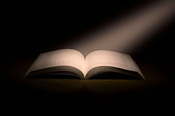 A captivating of an open book under a dramatic spotlight, symbolizing knowledge. HD wallpaper