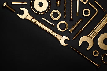 A collection of golden tools arranged in a flat lay on a black surface, perfect for industrial themes. HD wallpaper