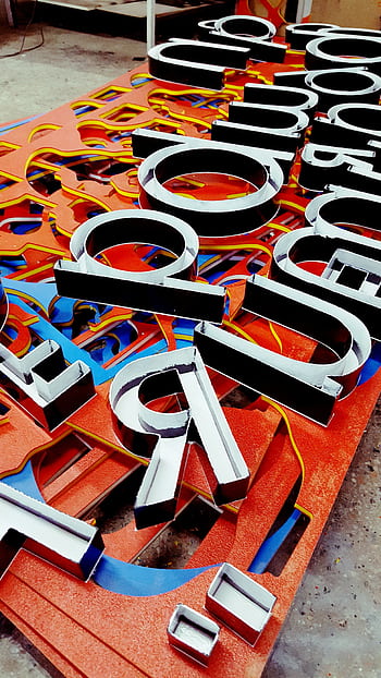 Vibrant neon letters arranged artistically, showcasing a unique signage design. HD phone wallpaper