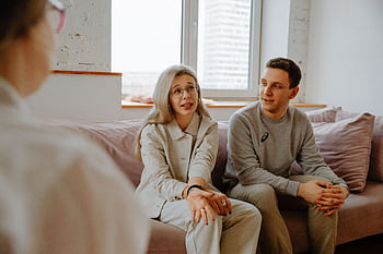 A couple and therapist engaged in a discussion during a therapy session indoors. HD wallpaper