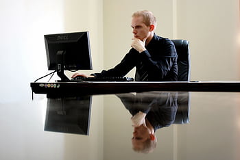 A businessman in deep thought at his desk, reflecting on work tasks. HD wallpaper
