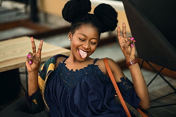 Joyful young woman making peace signs and posing playfully indoors. HD wallpaper