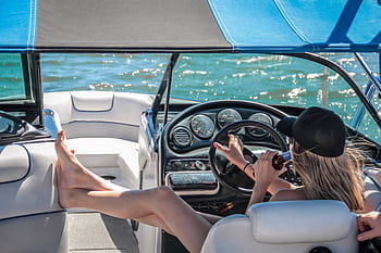 A woman enjoys a sunny day on a luxury boat, relaxing with a beverage. HD wallpaper