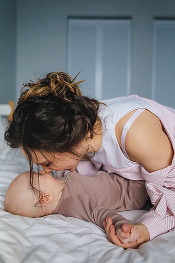 Mother shares a tender moment with her baby, lying together in a cozy and comfortable bedroom. HD phone wallpaper