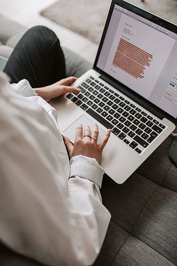 Woman working on a laptop indoors, focusing on document editing and remote work. HD phone wallpaper