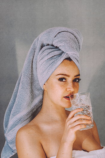 Woman with towel on head enjoying a refreshing glass of water against gray background. HD phone wallpaper