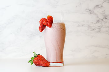 Delicious and creamy strawberry milkshake garnished with fresh berries on a white marble background. HD wallpaper