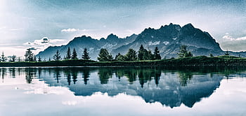 Stunning mountain landscape reflected in a serene lake under a clear sky. HD wallpaper