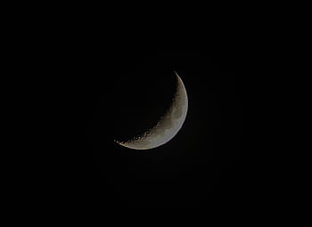 A crescent moon shines against a dark night sky, creating a serene lunar scene. HD wallpaper