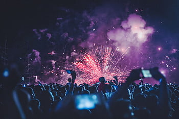 Dynamic crowd witnessing a vibrant fireworks display at a night festival, capturing the energy and joy of the event. HD wallpaper