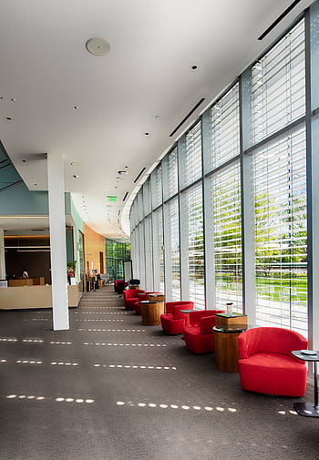 Spacious contemporary lobby with red lounge chairs and expansive windows for natural light. HD phone wallpaper