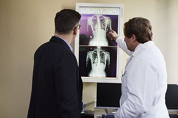 A doctor explains X-ray results to a patient in a clinical setting, highlighting healthcare communication. HD wallpaper