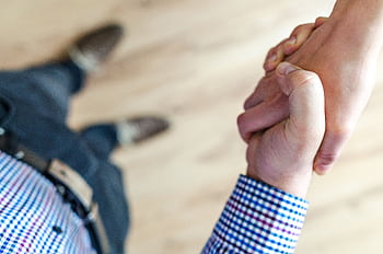 Close-up of a handshake between two people inside an office, symbolizing trust and cooperation. HD wallpaper