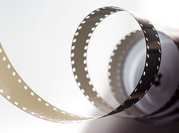 Close-up artistic view of a vintage filmstrip in a spiral design, highlighting its metallic texture. HD wallpaper