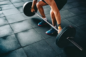 Young man lifting a heavy barbell during an intense indoor gym workout. HD wallpaper
