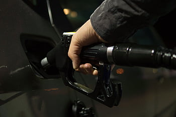 Close-up of a person refueling a car at a gas pump during night. HD wallpaper